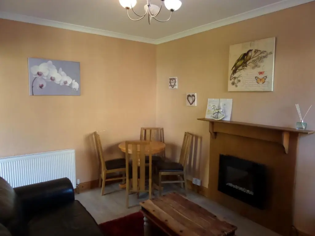 a living room with a table and a fireplace at Jane's Cottage Free Parking in Inverness