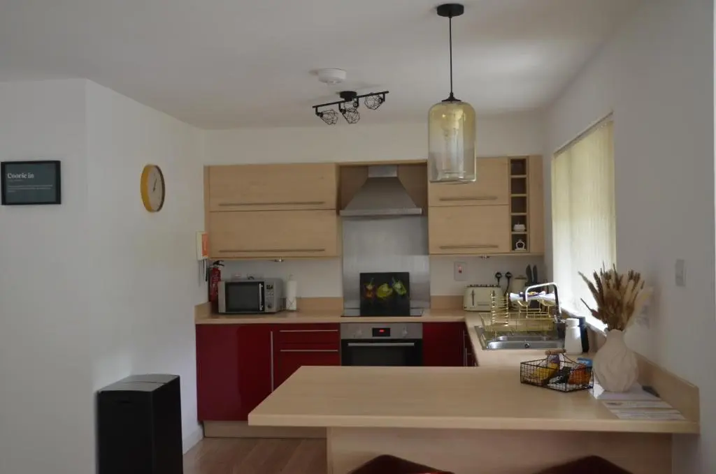 a kitchen with red cabinets and a wooden counter top at SCOTTISH HIGHLANDS Superb 2 bedroom apartment. in Invergarry