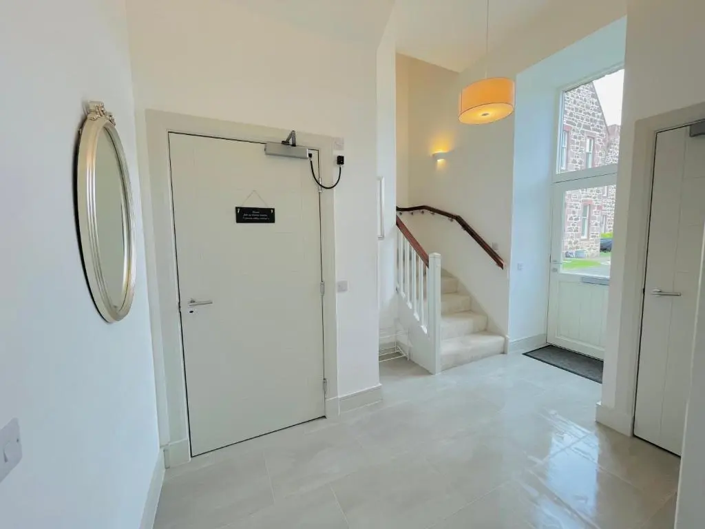 a hallway with a white door and a staircase at Great Glen Townhouse Inverness - Entire 3 Story Townhouse in Inverness