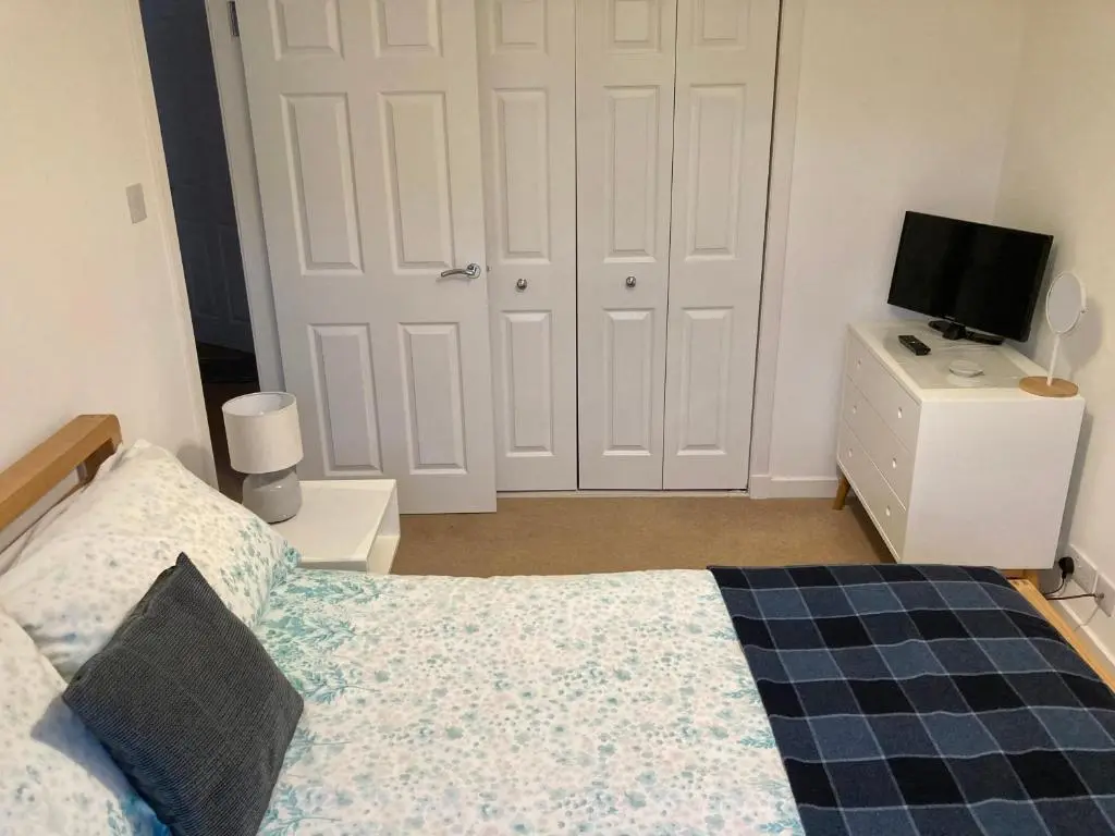 a bedroom with a bed and a tv on a dresser at 'Edgewood' - spacious detached bungalow in Inverness