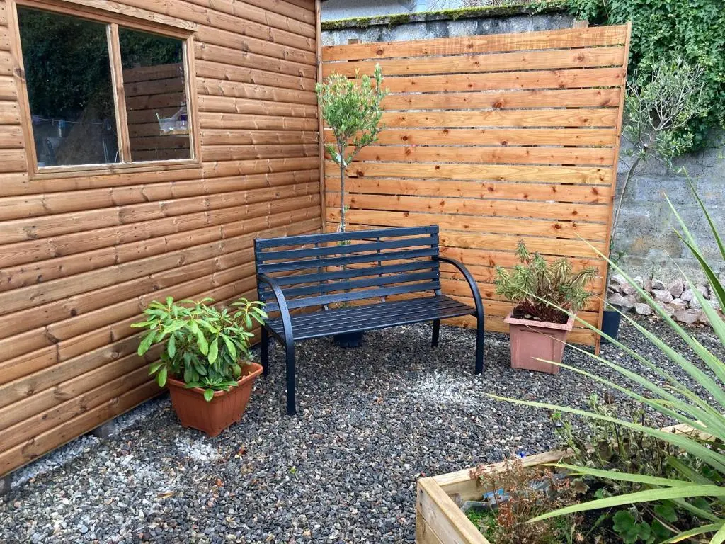 a bench sitting next to a wooden wall with potted plants at 'Edgewood' - spacious detached bungalow in Inverness