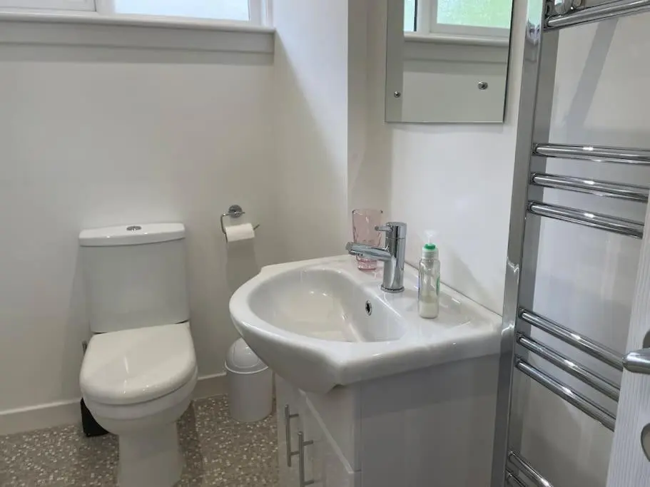 a white bathroom with a toilet and a sink at 'Edgewood' - spacious detached bungalow in Inverness