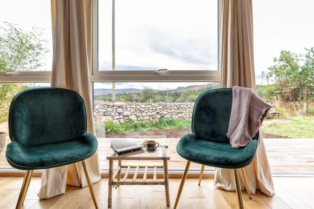 two green chairs in a room with a table at Alba - Charming boutique forest view cabin with hot tub in Ballater in Ballater