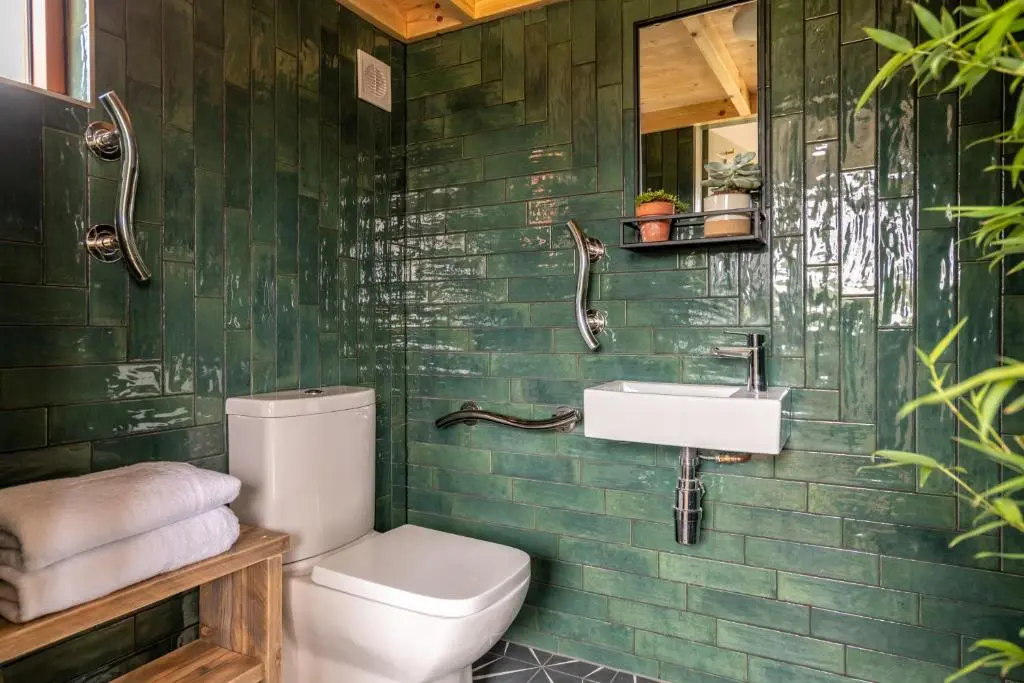 a green tiled bathroom with a toilet and a sink at Alba - Charming boutique forest view cabin with hot tub in Ballater in Ballater