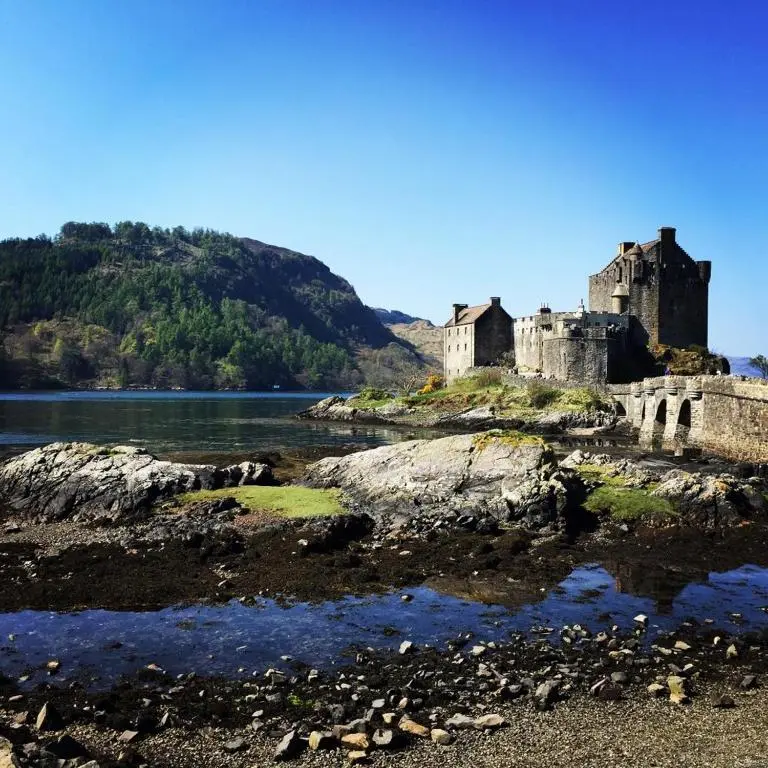 a castle on the shore of a body of water at Torgoyle Cottage in Inverness