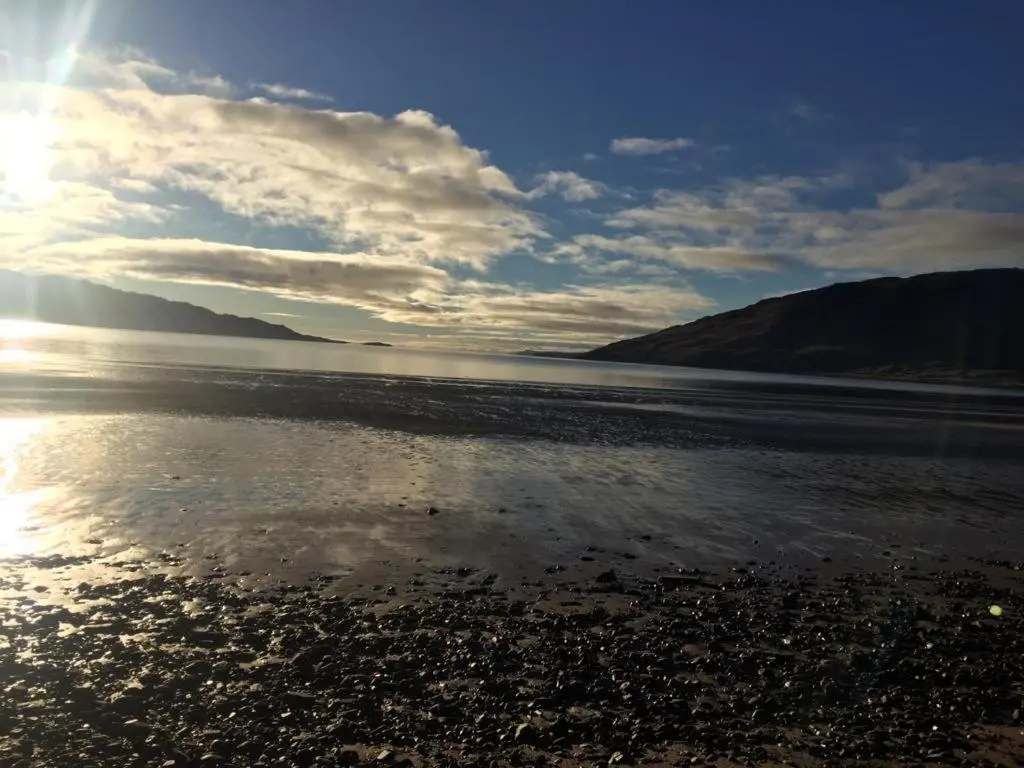 a beach with the sun reflecting in the water at Torgoyle Cottage in Inverness