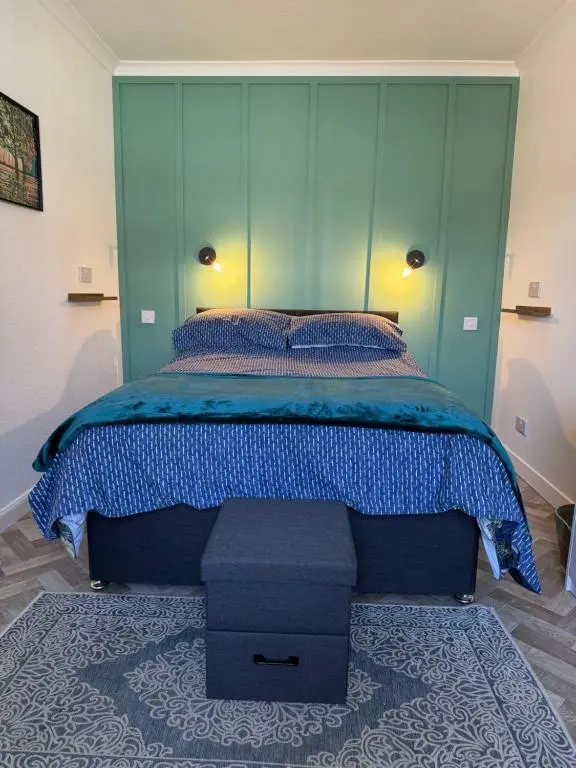 a bedroom with a large bed with a blue headboard at Helens Lybster cosy cottage on NC500 in Lybster