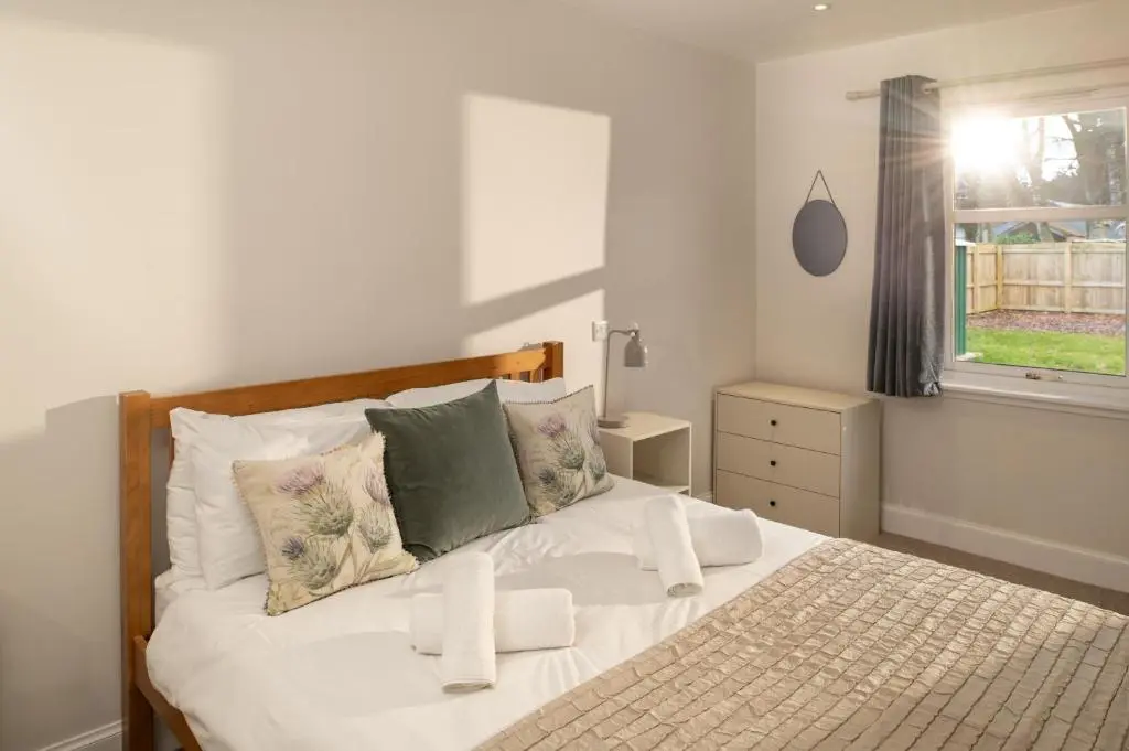 a bedroom with a white bed with pillows and a window at Anne's Place in Boat of Garten