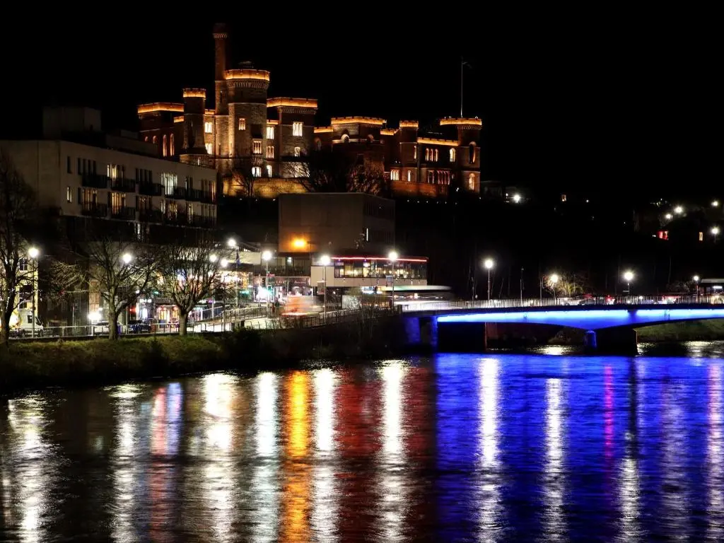 a bridge over a river with a city at night at Porter's Lodge in Inverness