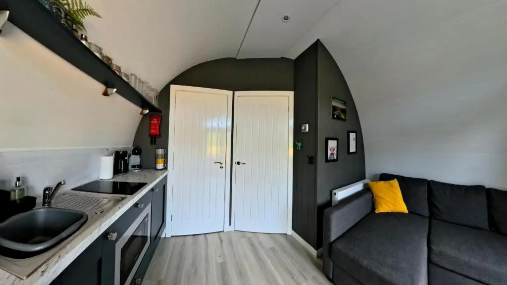 a living room with a couch and a sink in a room at Newmore Highland Pods with Hot Tubs on NC500 in Invergordon
