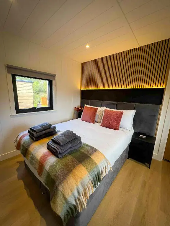 a bedroom with a large bed with towels on it at Newmore Highland Pods with Hot Tubs on NC500 in Invergordon