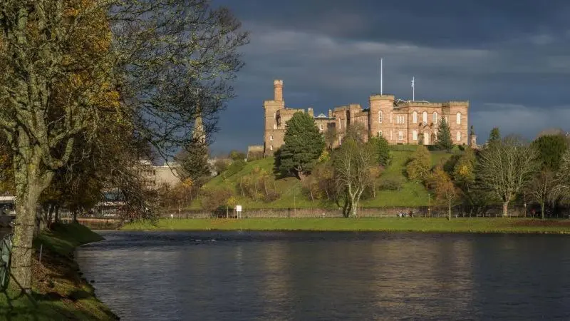 a castle sitting on top of a hill next to a lake at Stephen's Street Apartment, Inverness City Centre in Inverness