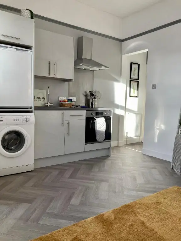 a kitchen with white cabinets and a washer and dryer at Haugh Ness in Inverness