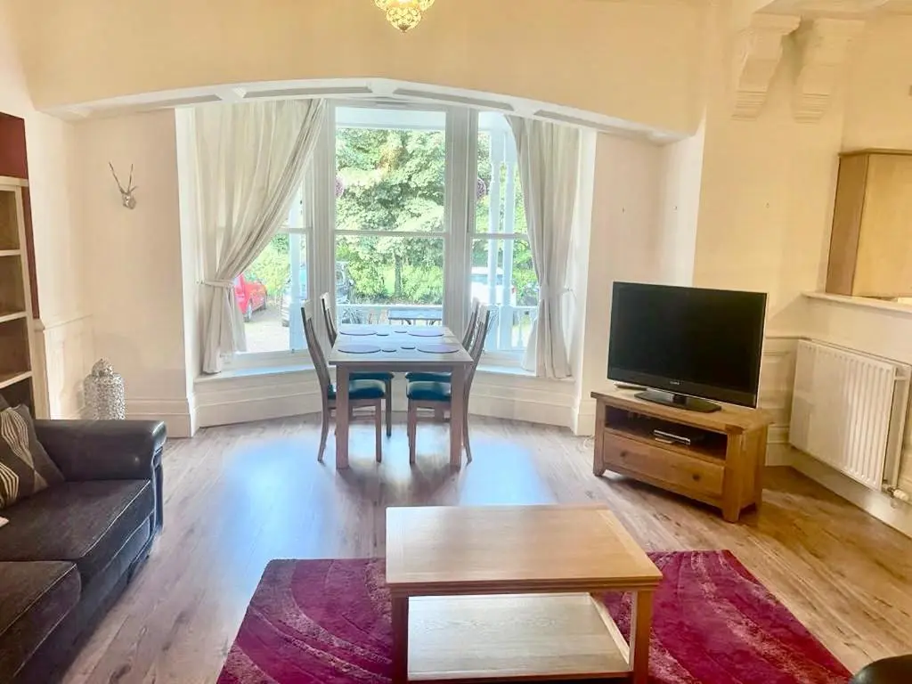a living room with a table and a tv at Serviced Accommodation Moray - Lesmurdie House No 2 in Elgin