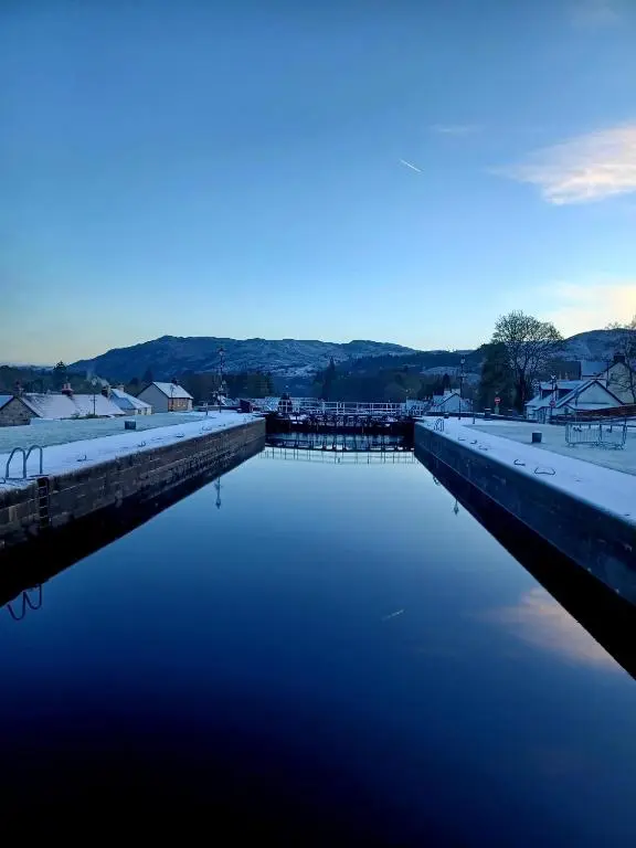 a body of water with snow on top of it at Erraid Lodge in Fort Augustus