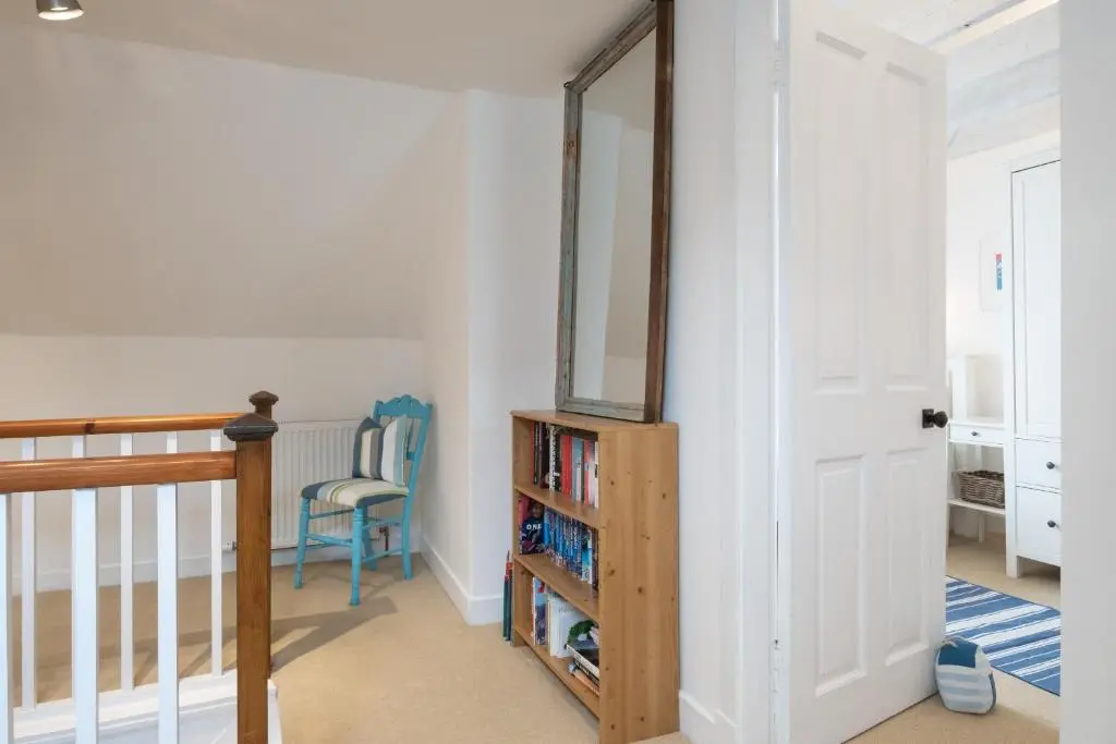 a hallway with a mirror and a chair in a room at Seaside cottage on Moray coast in Portknockie