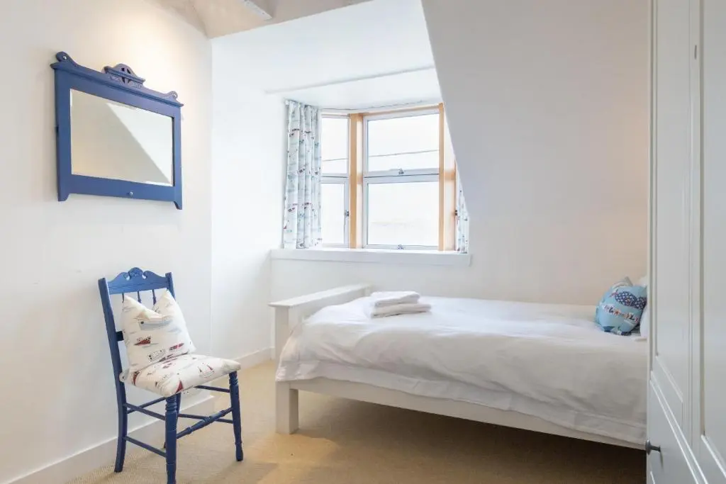 a bedroom with a bed and a mirror and a chair at Seaside cottage on Moray coast in Portknockie