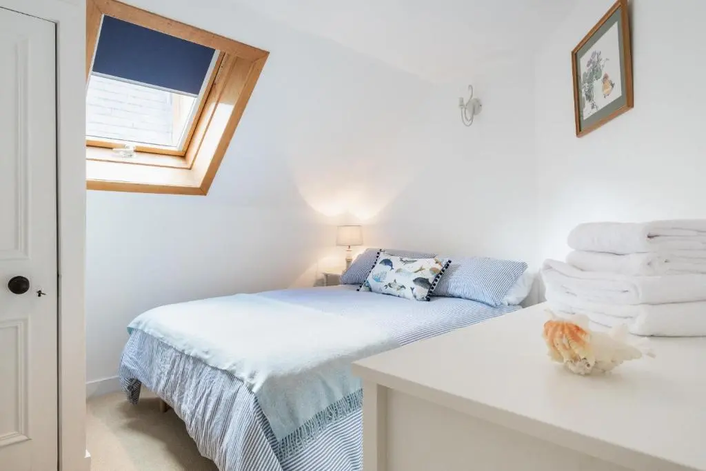 a bedroom with a bed and a window and towels at Seaside cottage on Moray coast in Portknockie