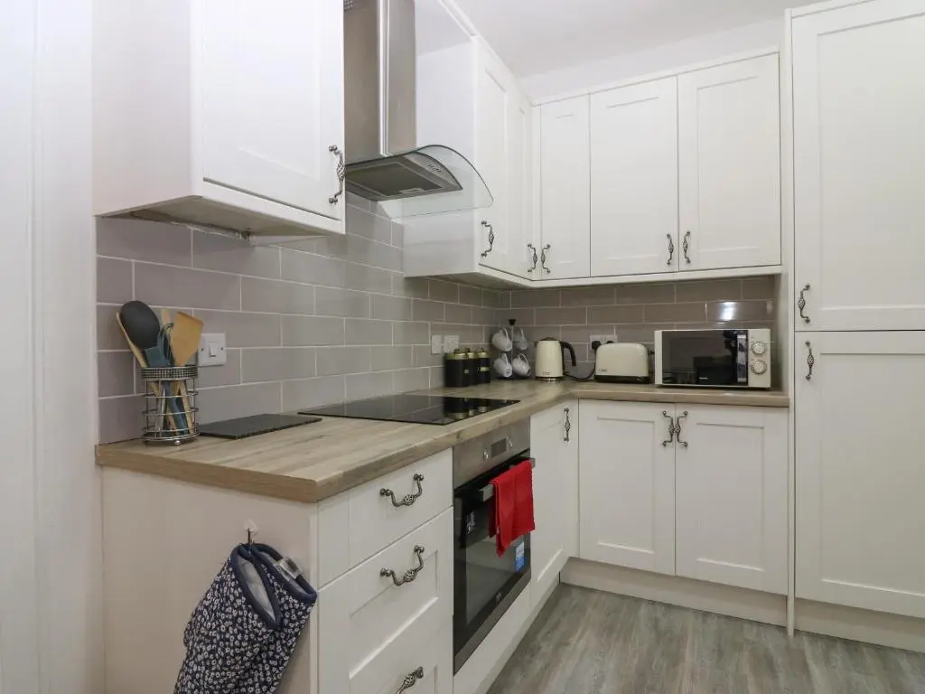 a white kitchen with white cabinets and appliances at RockStar Cottage in Macduff