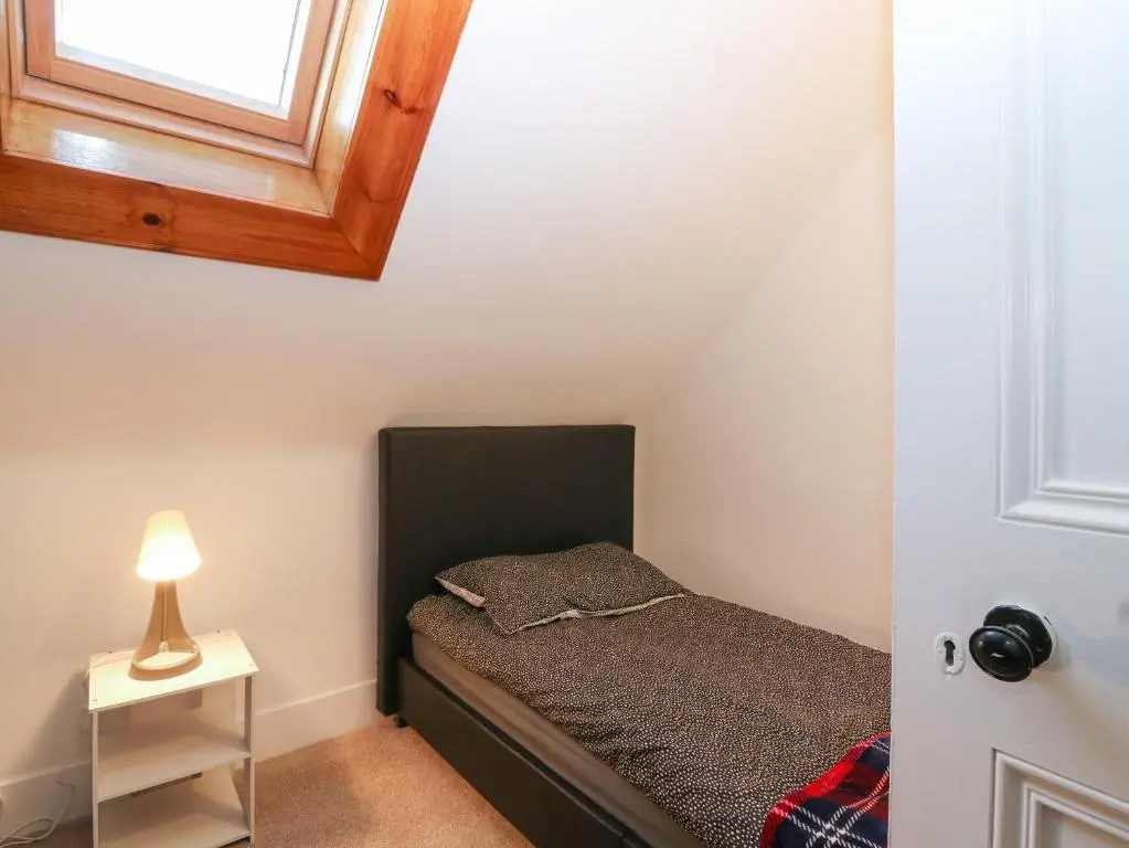 a small bedroom with a bed and a window at RockStar Cottage in Macduff