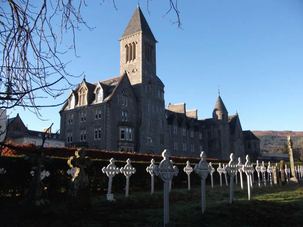 an old building with a clock tower in front of it at Raven Wing Apartments - Highland Club Scotland in Fort Augustus