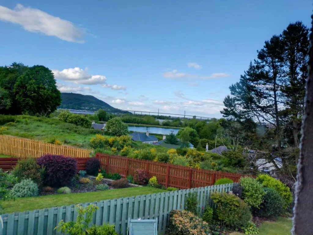 a garden with a white fence and flowers at Aber Holiday Rentals in Inverness