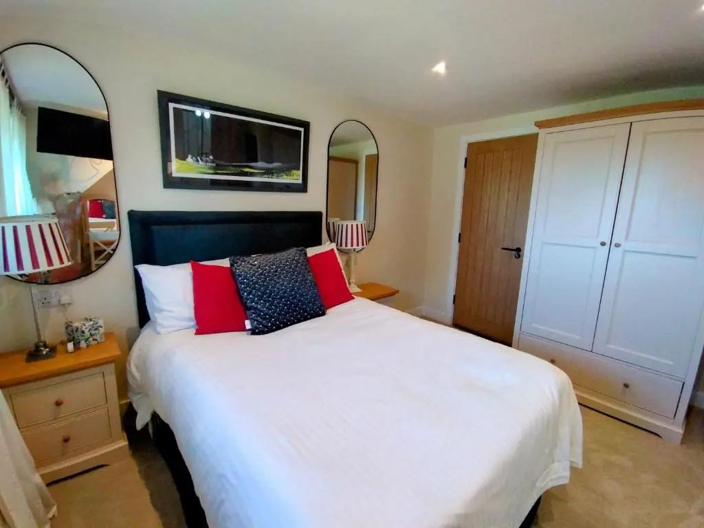 a bedroom with a large white bed with red pillows at Aber Holiday Rentals in Inverness