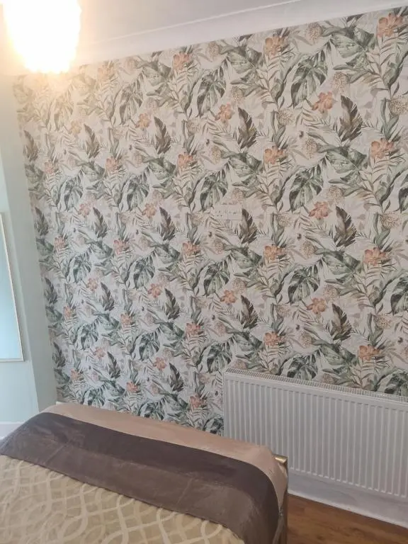 a bedroom with a wall with a floral wallpaper at Nanny Bambi's highland hoose in Inverness