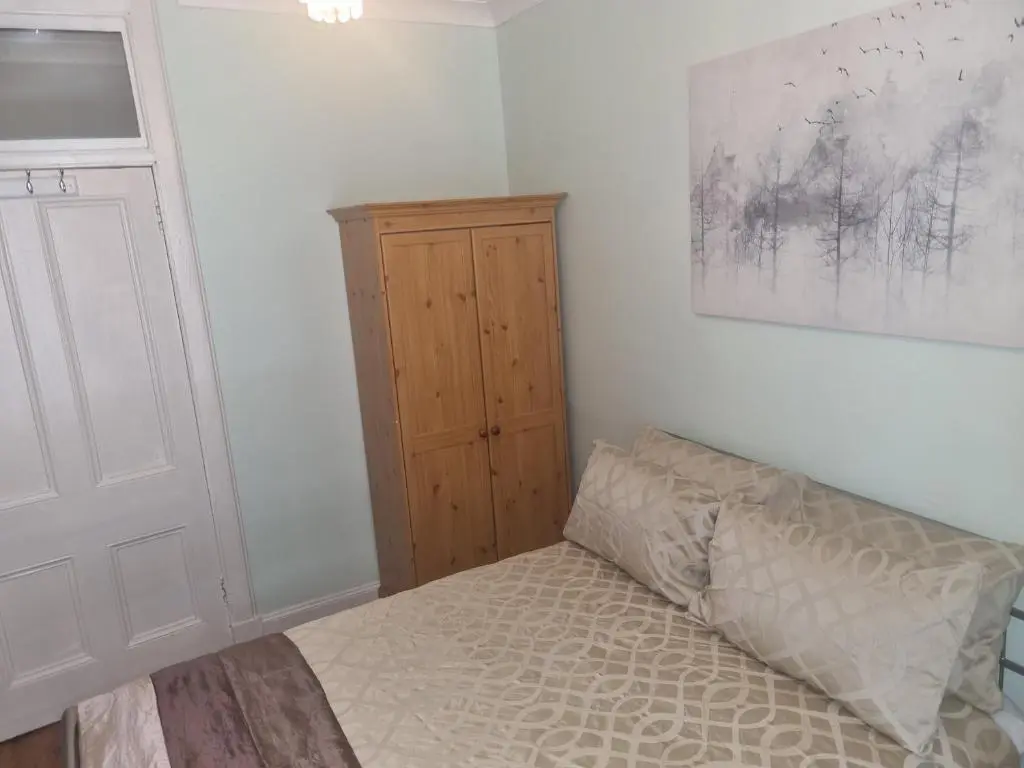 a bedroom with a bed and a wooden cabinet at Nanny Bambi's highland hoose in Inverness