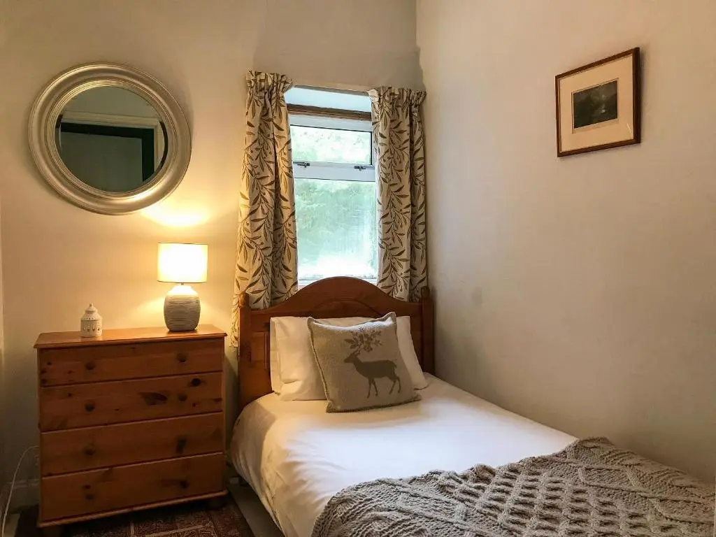 a bedroom with a bed and a dresser and a window at Tigh Beag in Newtonmore