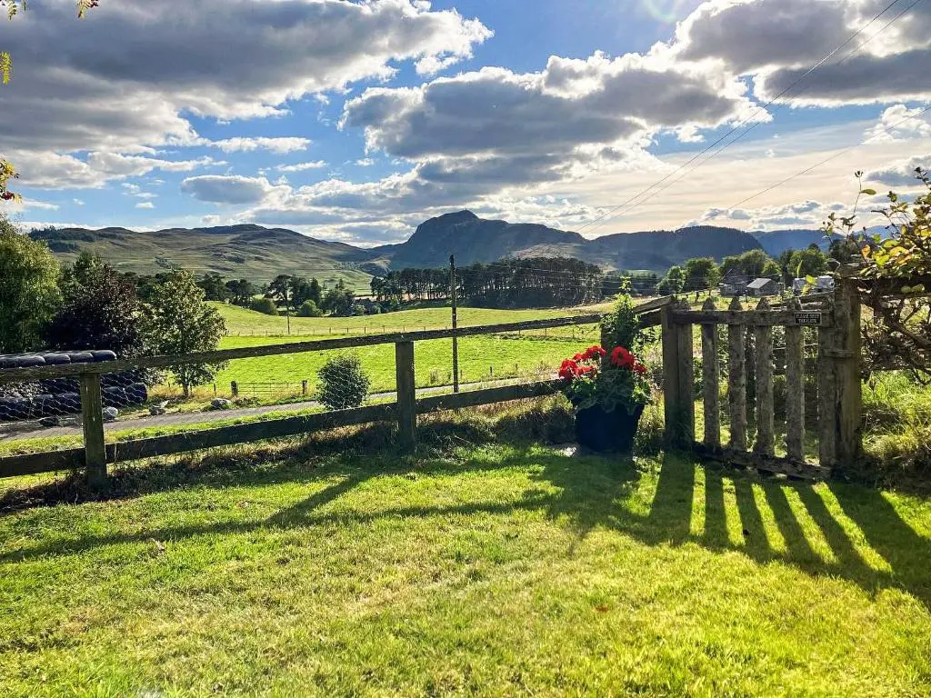 a wooden fence with flowers in a field at Tigh Beag in Newtonmore