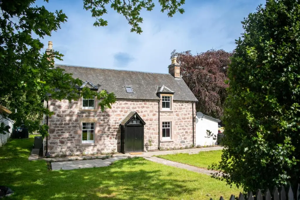 an old stone house with a green yard at Lock Keepers Cottage, Loch Ness Cottage Collection in Inverness