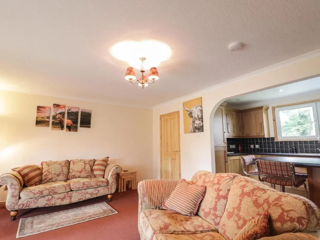 a living room with two couches and a table at Garden Lodge in Muir of Ord