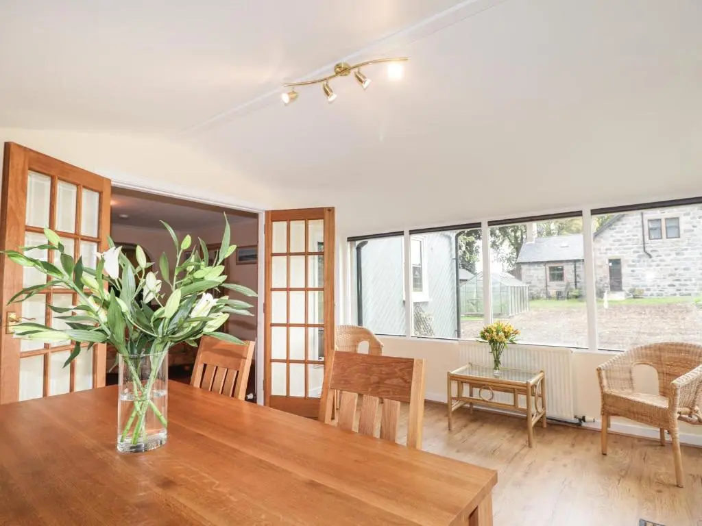 a dining room with a table with a vase of flowers at Garden Lodge in Muir of Ord
