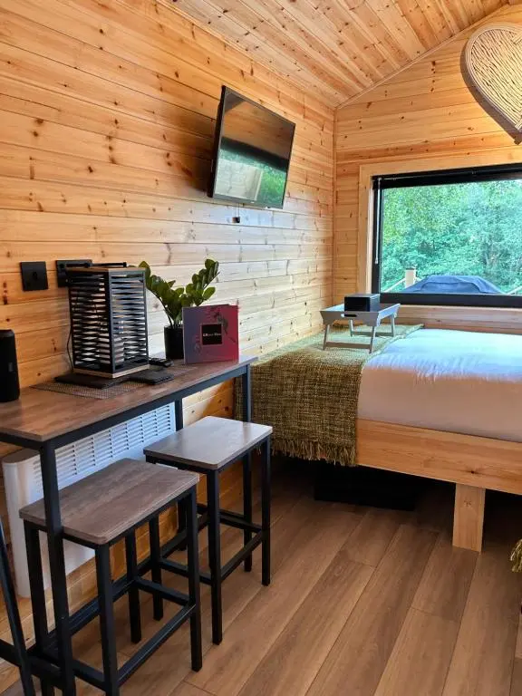 a bedroom in a log cabin with a bed and a desk at River Huts with Private Hot Tubs in Inverness