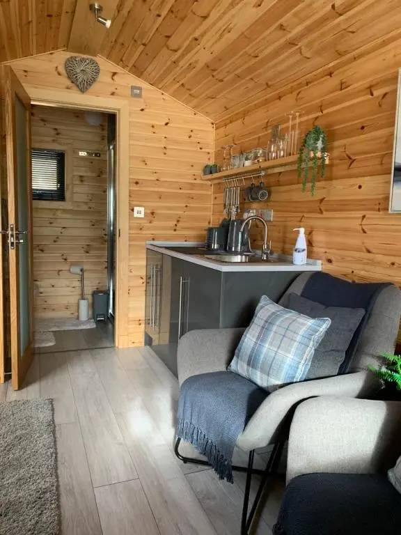 a living room with a couch and a kitchen at River Huts with Private Hot Tubs in Inverness