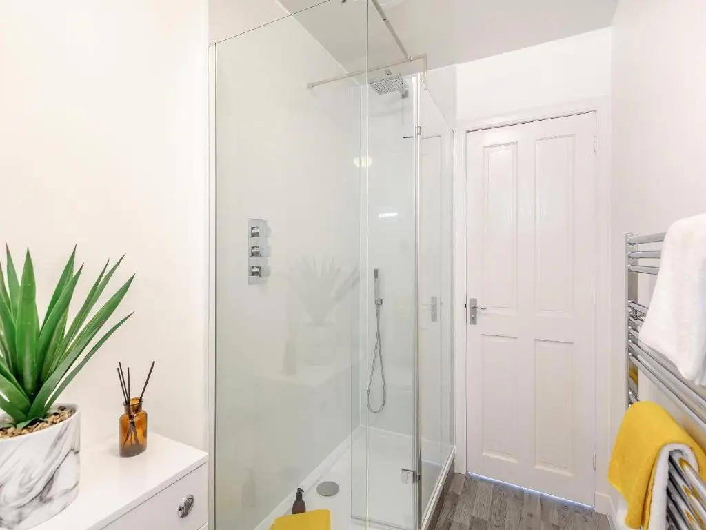 a white bathroom with a glass shower stall at Dove Cottage in Inverness
