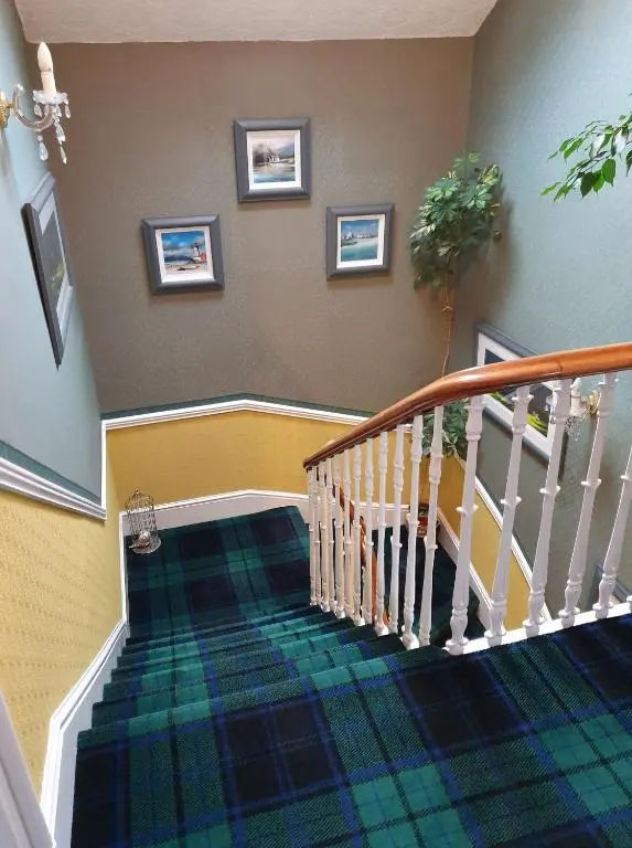 a hallway with a staircase with a plaid carpet at Moyness House in Inverness