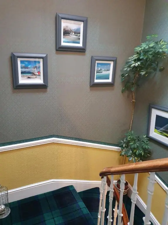a staircase with three pictures on the wall at Moyness House in Inverness