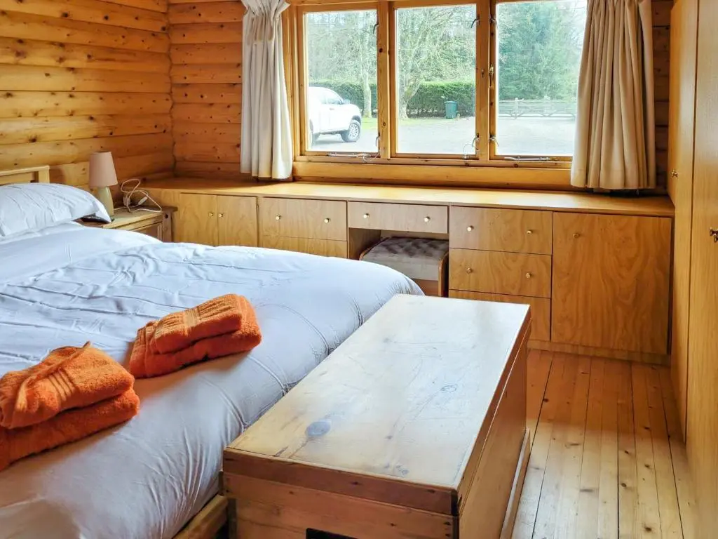 a bedroom with a bed and a table in a cabin at Ardle Lodge in Enochdhu