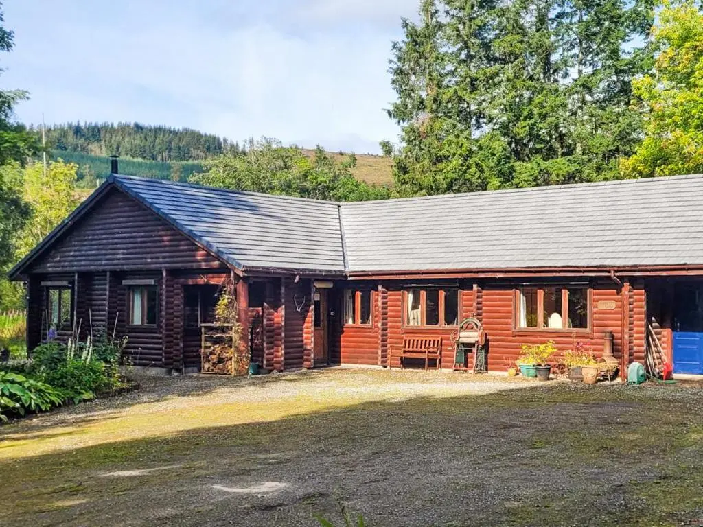 a log cabin with a bench in front of it at Ardle Lodge in Enochdhu