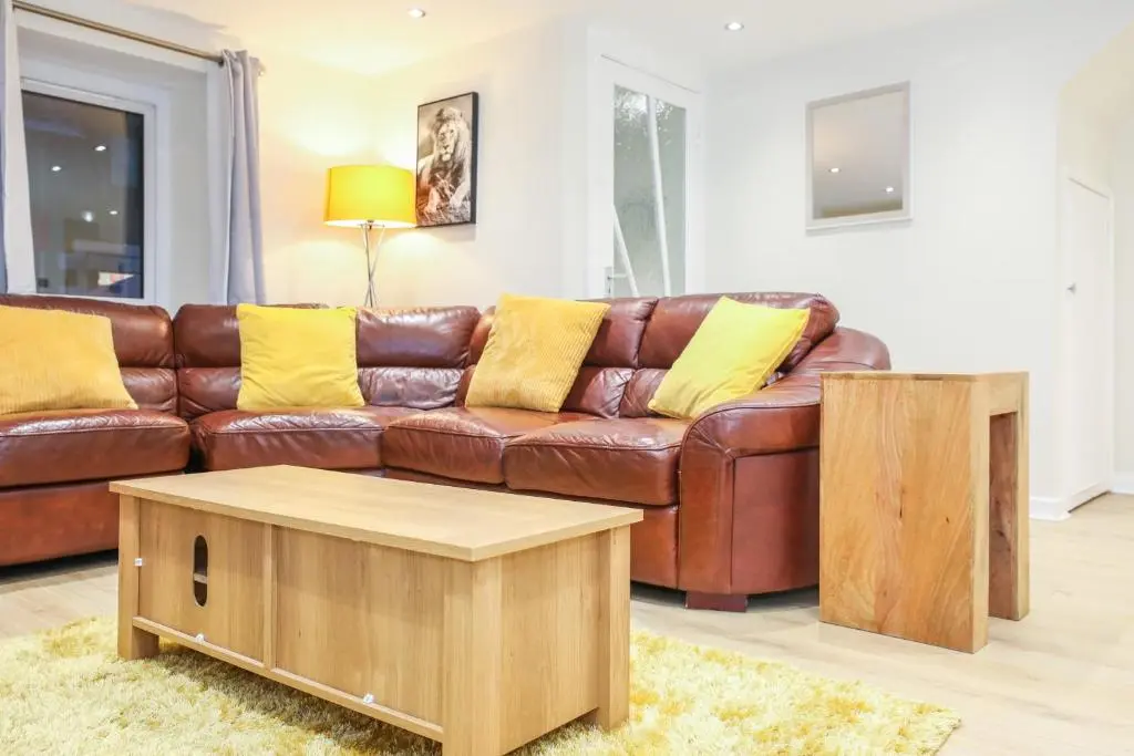 a living room with a brown leather couch and a coffee table at mySTAYINN Tomnahurich Guest House in Inverness