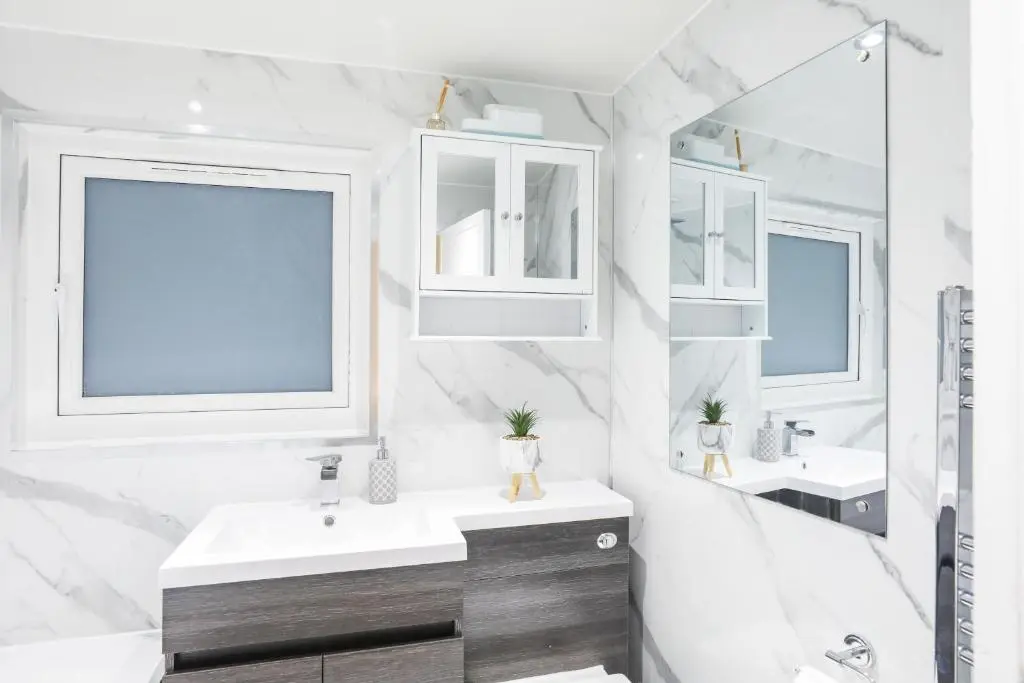 a white bathroom with two sinks and two mirrors at mySTAYINN Tomnahurich Guest House in Inverness