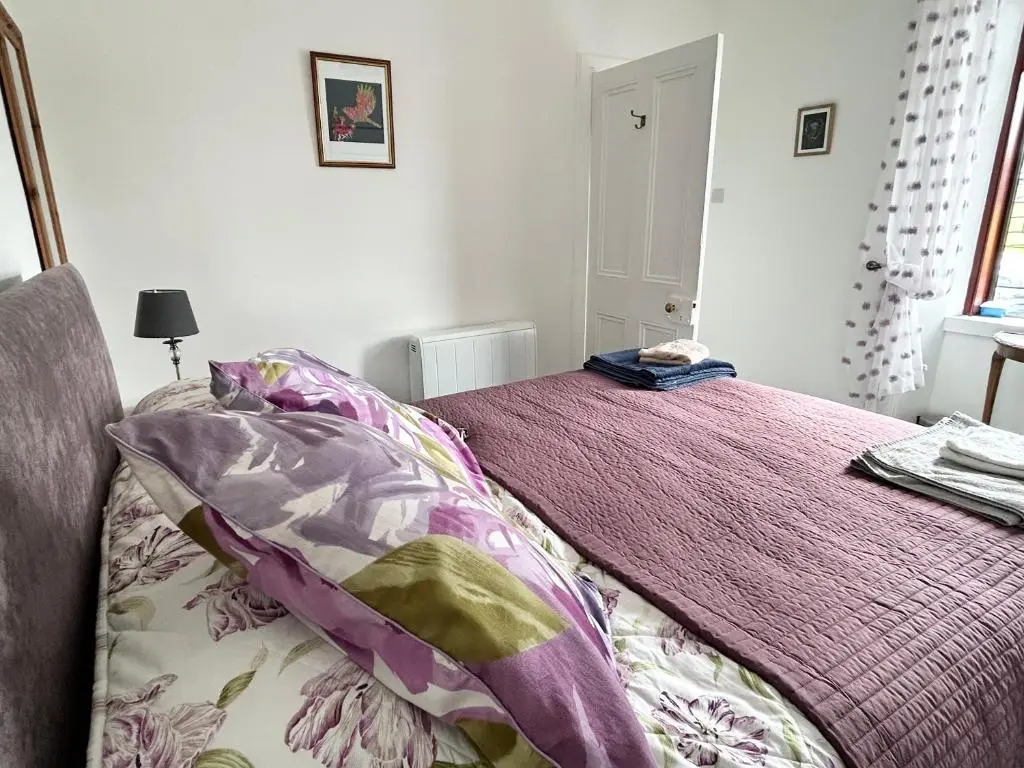 a bedroom with a bed with a purple blanket at Lottie\u2019s Cottage, Rhynie, Aberdeenshire in Rhynie