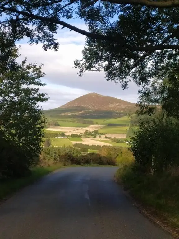 an empty road with mountains in the distance at Lottie\u2019s Cottage, Rhynie, Aberdeenshire in Rhynie