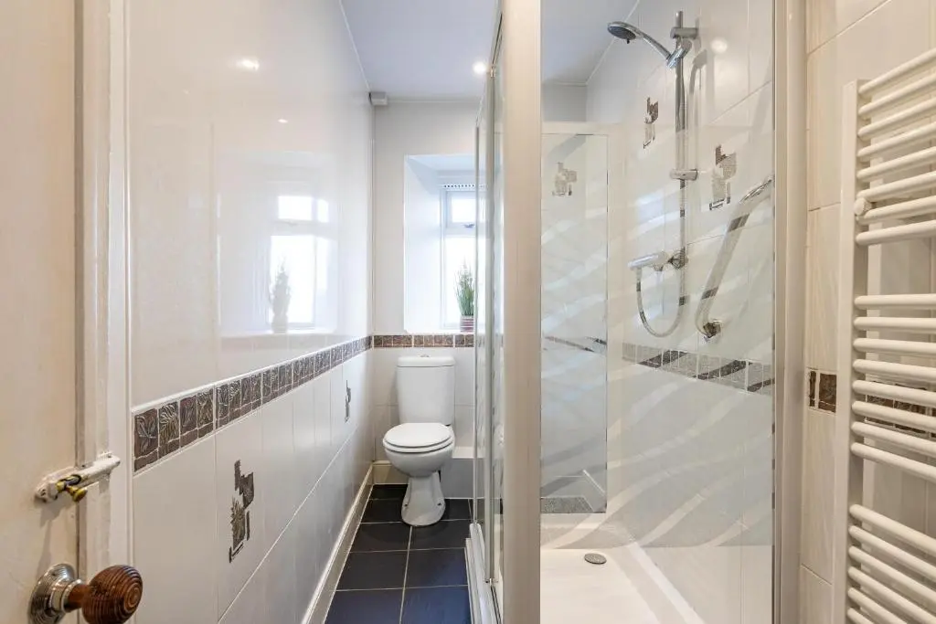 a white bathroom with a toilet and a shower at Thistle do Nessly in Inverness
