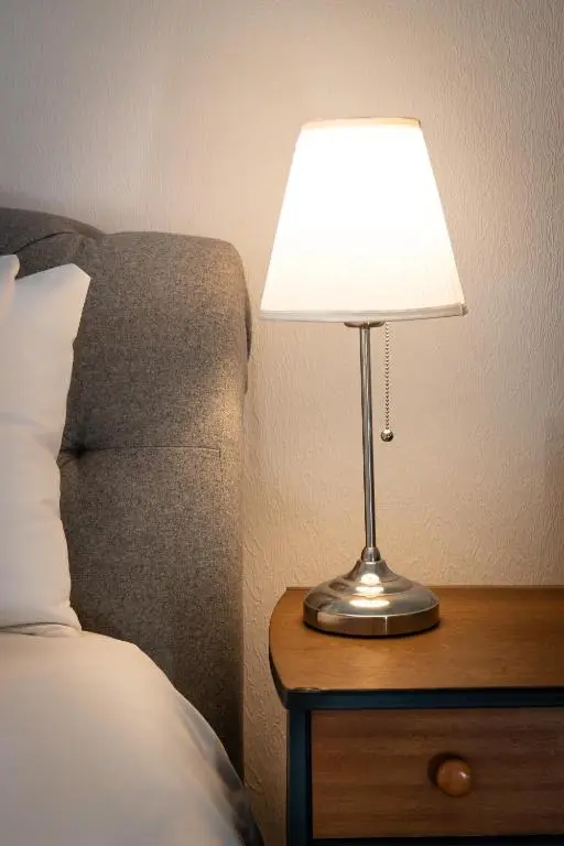 a lamp on a night stand next to a bed at Thistle do Nessly in Inverness