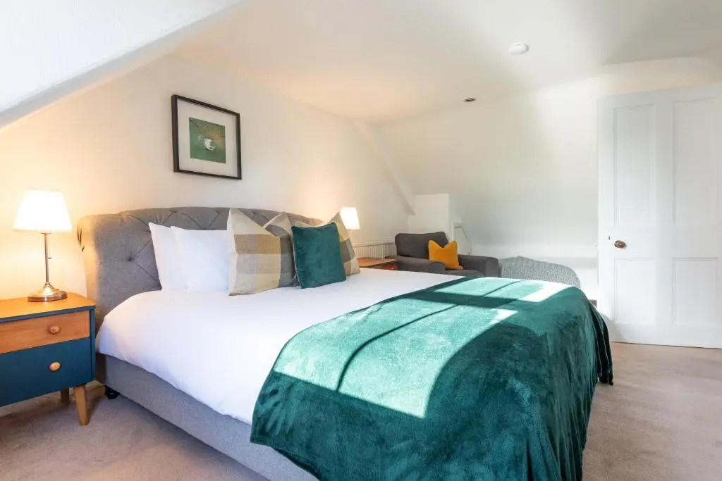 a bedroom with a bed with a green blanket on it at Thistle do Nessly in Inverness