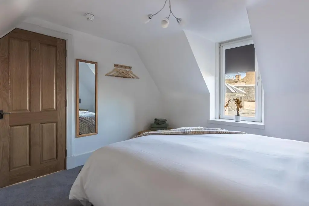 a bedroom with a large white bed and a window at Hill Street Haven in Inverness