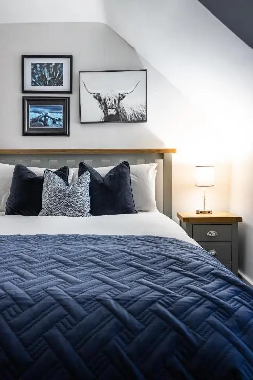 a bedroom with a bed with a blue comforter at Hill Street Haven in Inverness